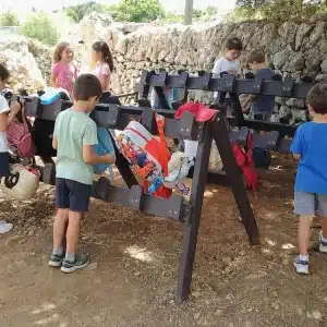Detalle de niños usando el perchero ecológico de plástico reciclado