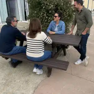 Detalle de mesa picnic accesible con personas charlando en calle de ciudad