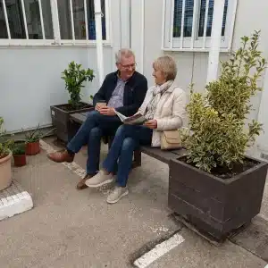 personas sentadas en banco ecológico de plástico reciclado con jardineras